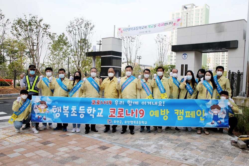 행복초등학교 코로나19 예방 캠페인 현수막과 함께 단체사진을 남기는 모습