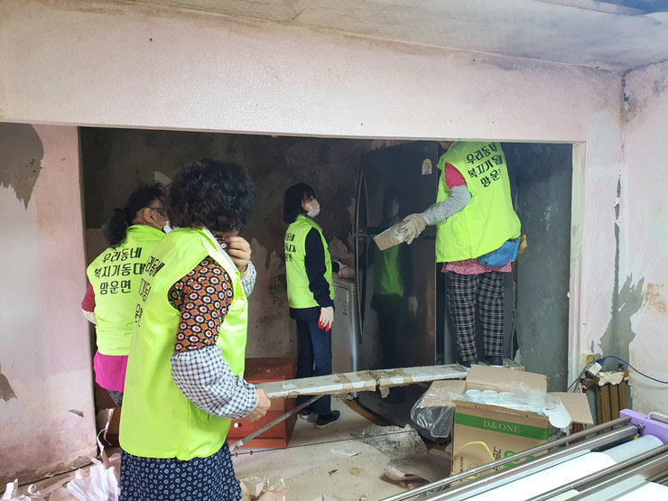 등판에 우리동네 복지기동대 망운면 이라고 적힌 형광색 조끼를 입고 기동대원들이 낡은 집을 수리하고 있는 모습이다. 