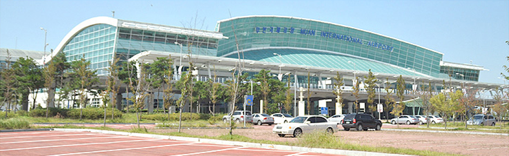 무안 국제공항 전경으로, 주차장이 보이고 그 뒤로 무안국제공항 건물이 보인다.